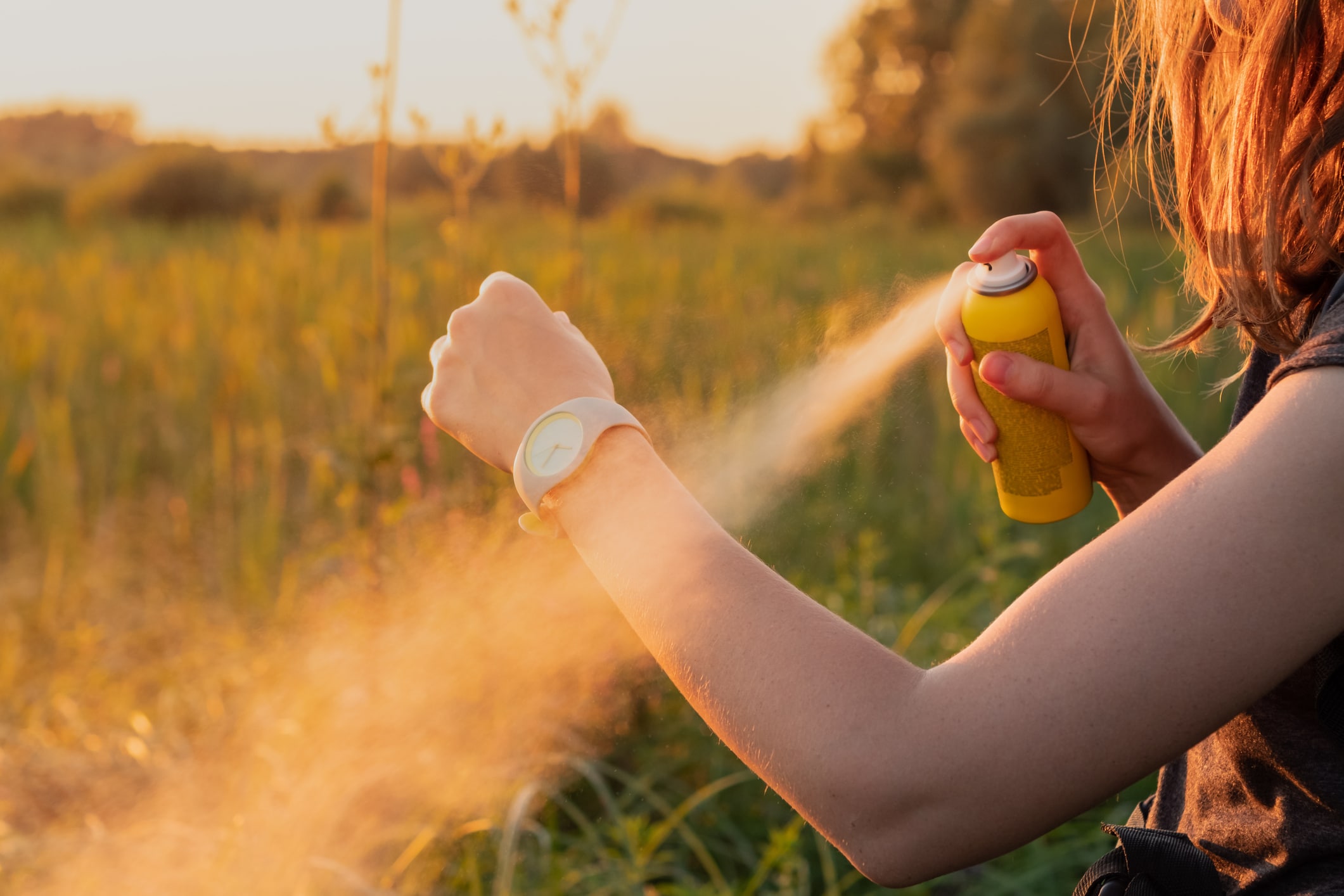 spraying bug spray on arm